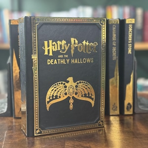 May include: A black hardback book with gold lettering and a gold design on the front cover. The title is "Harry Potter and the Deathly Hallows".