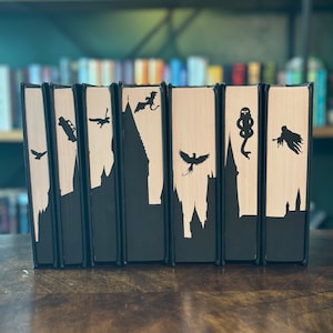 May include: Set of eight decorative bookends featuring black silhouettes of Harry Potter characters and symbols on a cream background. The bookends are made of wood and are approximately 15cm tall.