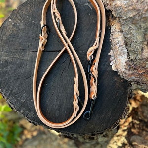 May include: Two brown leather dog leashes with black metal clasps and rings. The leashes are braided and have a smooth finish.