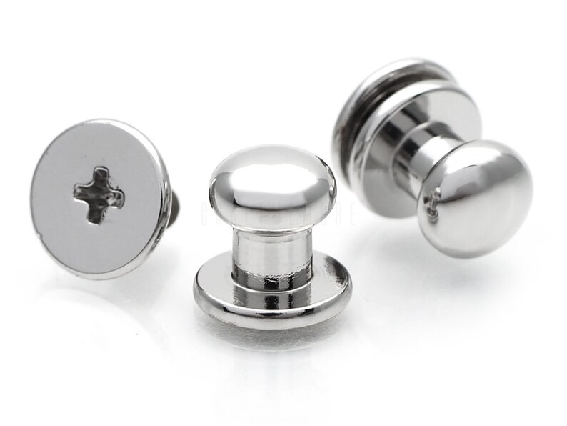May include: Three silver metal push button fasteners with a round head and a flat base. The fasteners have a cross-shaped slot for a screwdriver.