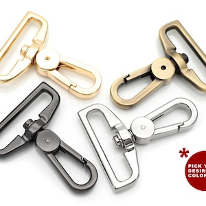 Könnte beinhalten: Vier schwenkbare Karabinerhaken in verschiedenen Ausführungen: Gold, Antikmessing, Silber und Schwarz. Die Karabinerhaken sind aus Metall und haben eine T-förmige Schlaufe.