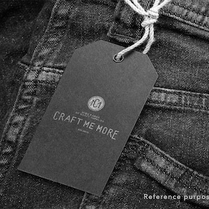 May include: Black and white tag with the text "Craft Me More" and a logo that says "NC1 Wide Range Of Craft Supplies Est. 2013" attached to a pair of black denim jeans.