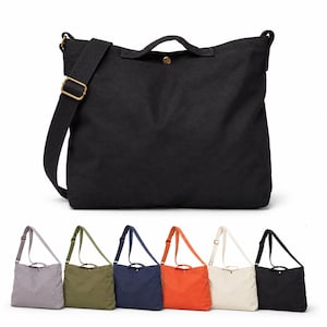 Peut inclure: Un grand sac fourre-tout en toile noire avec une poignée supérieure, une bandoulière et une fermeture à pression en métal couleur laiton. En dessous, une rangée de six sacs identiques en gris, vert olive, bleu marine, orange, blanc cassé et noir.