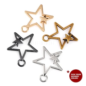 Op de afbeelding: Drie metalen stervormige bedels met een kleinere ster erin. De bedels zijn verkrijgbaar in goud, zilver en zwart.