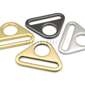 May include: Three triangle-shaped metal slider buckles in gold, silver, and black.