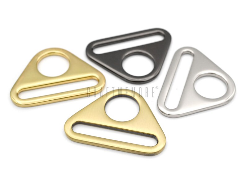May include: Three triangle-shaped metal slider buckles in gold, silver, and black.