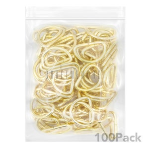 May include: A clear plastic bag filled with 100 gold-coloured metal D-rings. The bag has a zipper closure and the text "100Pack" is printed on the bottom of the bag.