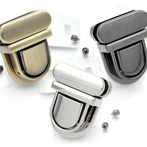 Pode incluir: Três fechos de bolsa de metal em acabamentos latão antigo, preto e prata. Cada fecho tem uma parte superior retangular e uma parte inferior arredondada.