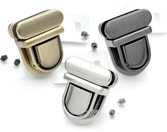 May include: Three metal purse clasps in antique brass, black, and silver finishes. Each clasp has a rectangular top and a rounded bottom.