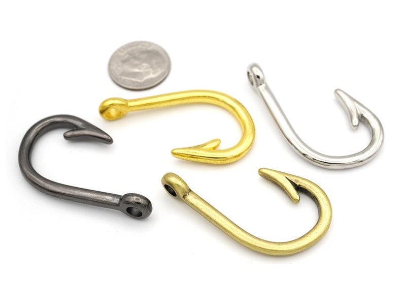 May include: Four different metal fishing hooks in various finishes: gold, silver, and black. The hooks are all in the shape of a traditional fishing hook with a curved point.
