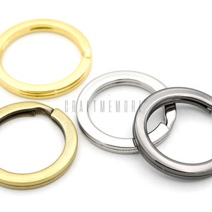 May include: Four key rings in different finishes: gold, brass, silver, and black. The key rings are all round and have a simple design.