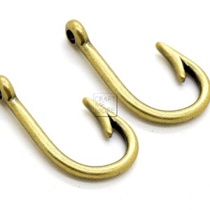 May include: Two gold-toned metal fishing hook charms. The hooks are about 2 inches long and have a smooth, shiny finish.