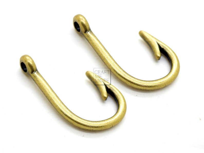 May include: Two gold-toned metal fishing hook charms. The hooks are about 2 inches long and have a smooth, shiny finish.
