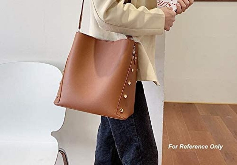 May include: A brown leather tote bag with a shoulder strap and gold accents. The bag has a zipper closure and a spacious interior.