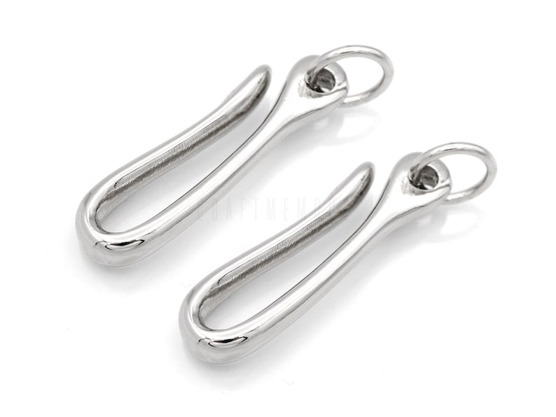 Pode incluir: Dois fechos de lagosta de metal prateado com acabamento arredondado e liso. Cada fecho tem um anel circular na parte superior.