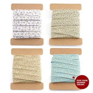 Pode incluir: Quatro rolos de fita com padrão floral em diferentes cores: branco com flores roxas, verde com flores azuis, amarelo com flores vermelhas e azul com flores amarelas. Escolha a cor que você deseja!