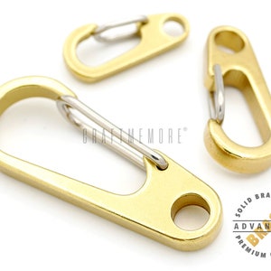 Può includere: Tre portachiavi in metallo color oro con chiusura a molla. I portachiavi sono in ottone massiccio e hanno una finitura di alta qualità.