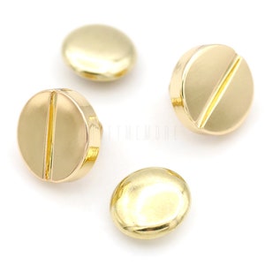 May include: Four gold-colored metal buttons with a raised line across the center. The buttons are round and have a smooth, shiny finish.