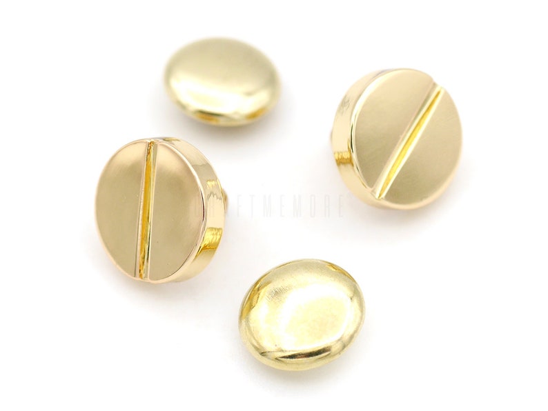 May include: Four gold-colored metal buttons with a raised line across the center. The buttons are round and have a smooth, shiny finish.
