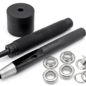 May include: A set of black metal tools for installing eyelets, including a hammer, a punch, and a set of eyelets. The eyelets are silver and come in different sizes.