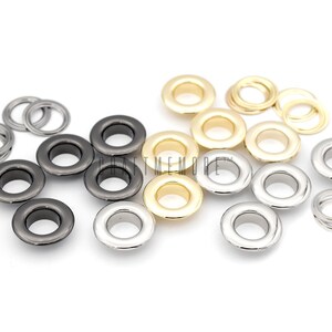 Pu&ograve; includere: Assortimento di occhielli metallici in tre colori: argento, oro e nero. Gli occhielli sono disposti in gruppi di tre, con ogni gruppo che contiene un colore diverso. Gli occhielli sono utilizzati per unire tessuto o altri materiali.