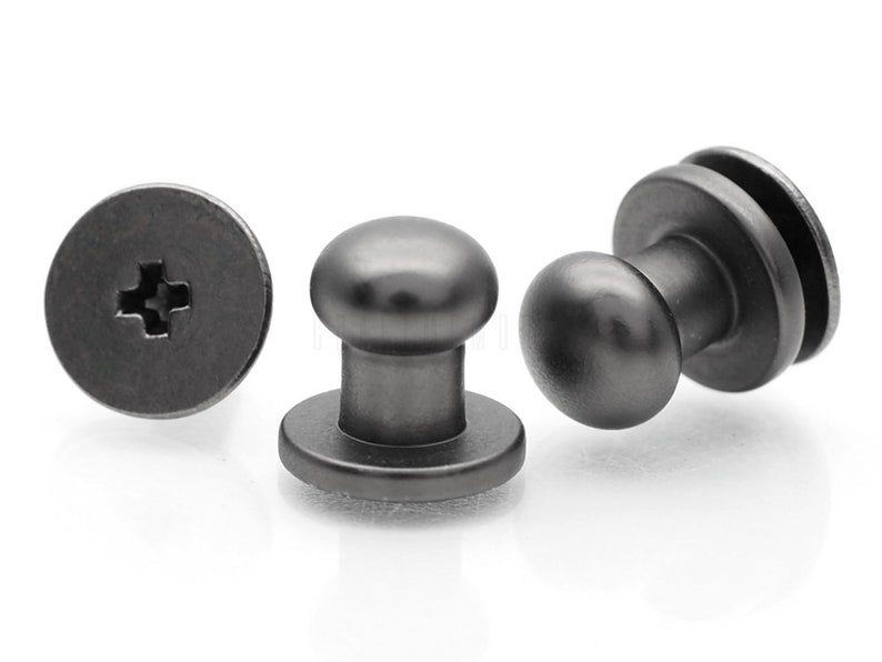 May include: Three black metal push button fasteners. Each fastener has a round head and a flat base with a cross-shaped slot for a screwdriver.