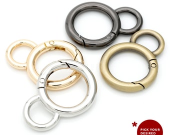 May include: Four metal key rings in different finishes: silver, gold, antique brass, and black. Each ring has a smaller loop attached to the larger ring.