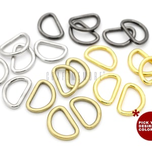 May include: Assortment of D-rings in silver, gold, and gunmetal finishes. The metal rings are displayed on a white background. The image includes a red circle with the text "PICK YOUR DESIRED COLOR!"
