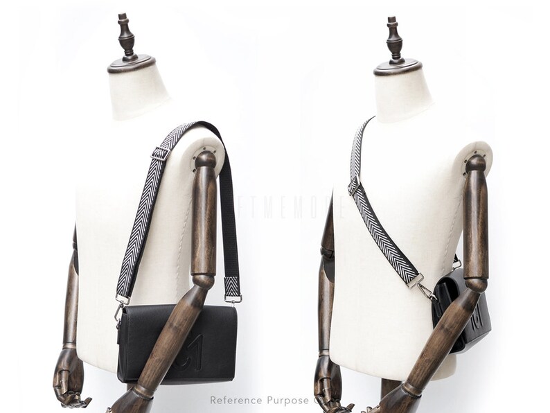May include: A black leather crossbody bag with a black and white chevron patterned strap. The bag is shown on a white mannequin.