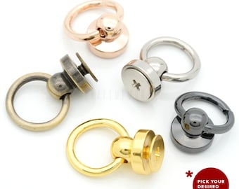 Könnte beinhalten: Fünf schwenkbare Druckknöpfe in verschiedenen Farben: Gold, Silber, Bronze, Schwarz und Roségold. Jeder Druckknopf hat einen runden Ring und eine Schraubbasis.