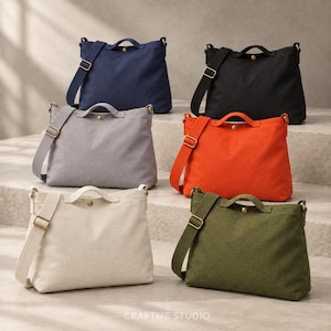 Pode incluir: Seis bolsas tiracolo de lona nas cores azul-marinho, preto, cinza, laranja, creme e verde-oliva. Cada bolsa possui uma alça superior, alça de ombro ajustável com ferragens douradas e um fecho de botão de pressão. Texto CRAFTME STUDIO visível.