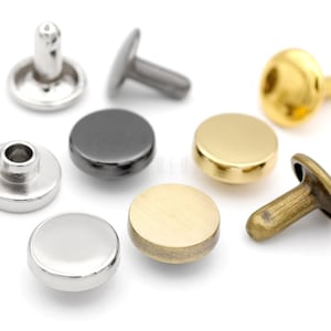 May include: Assortment of metal rivets in various finishes, including silver, gold, and black. The rivets have a round head and a post for attaching to fabric or leather.