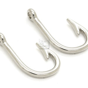 May include: Two silver-toned metal fishing hook charms. The hooks are about 1 inch long and have a smooth, shiny finish.