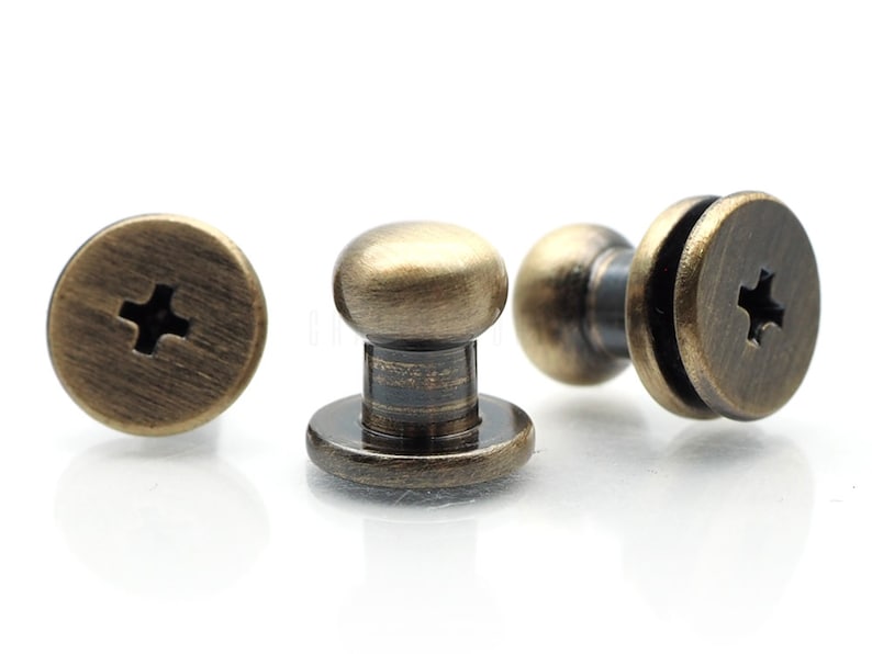 May include: Three antique gold-toned metal screw-on push buttons with a cross-shaped slot in the top.