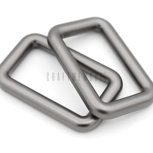 May include: Two silver metal D-rings, stacked on top of each other. The rings are rectangular in shape with rounded corners.