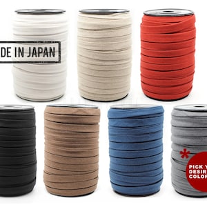 May include: Assortment of 10 spools of fabric trim in various colours, including black, white, beige, red, blue, and grey. The spools are labelled "Made in Japan".