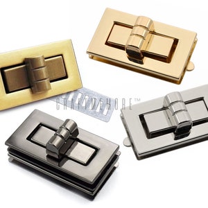 May include: Three rectangular metal clasps in gold, silver, and gunmetal finishes. Each clasp has a hinged top and a decorative, cylindrical knob.