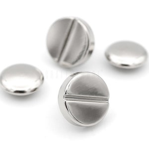 May include: Three silver metal buttons with a flat, round shape and a groove across the center.