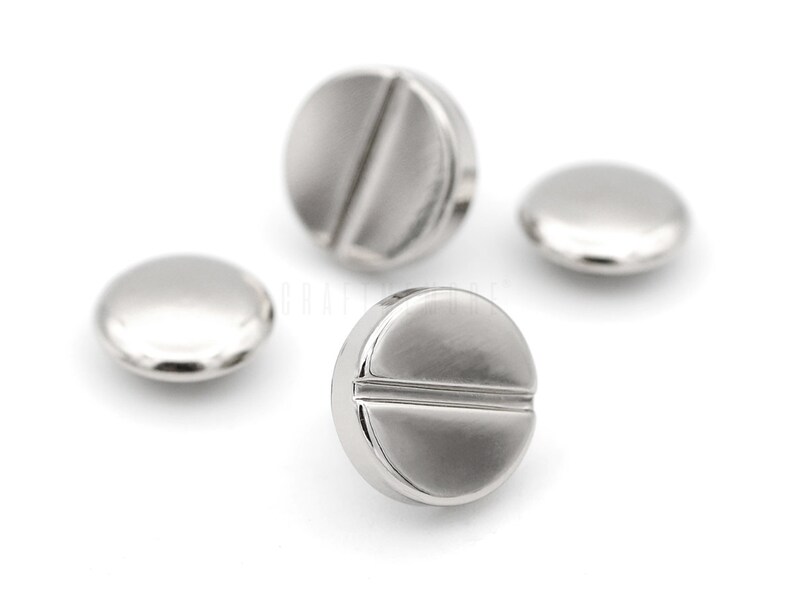 May include: Three silver metal buttons with a flat, round shape and a groove across the center.