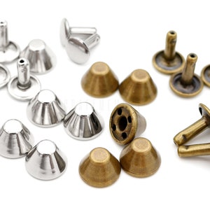 May include: Assortment of metal rivets in silver and antique brass finishes. The rivets have a cone-shaped head and a post with a flat base.