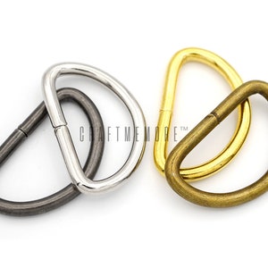 May include: Three metal D-rings in different finishes: silver, antique brass, and gold. The rings are approximately 2.5 cm in diameter.