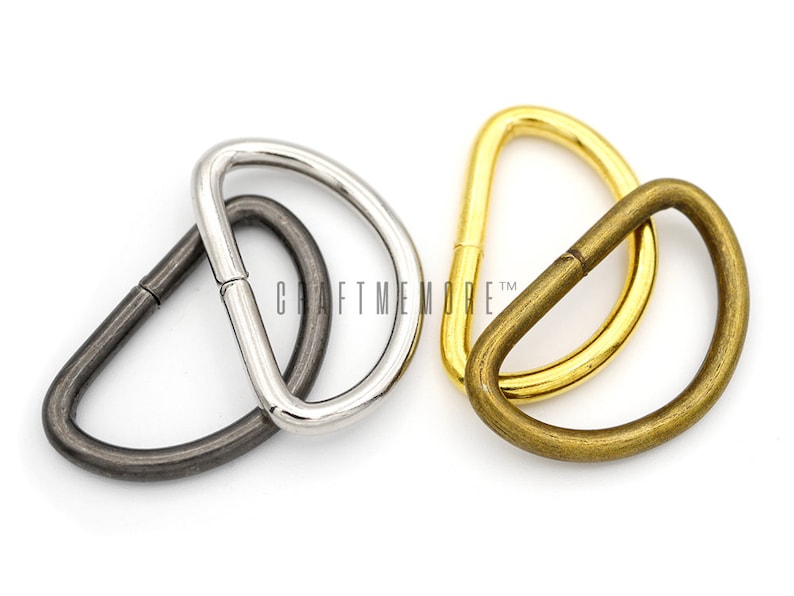 May include: Three metal D-rings in different finishes: silver, antique brass, and gold. The rings are approximately 2.5 cm in diameter.