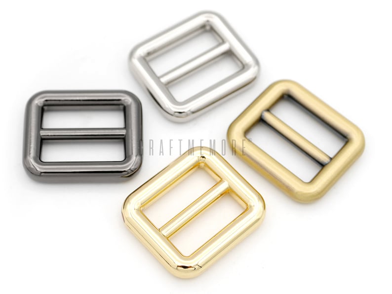 May include: Three metal slider buckles in different finishes: silver, black, and gold. Each buckle is square-shaped with a rectangular opening and a bar across the middle.