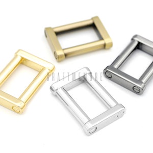 May include: Three metal D-rings in gold, silver, and black. The rings are all the same size and shape, and they have a smooth, polished finish.
