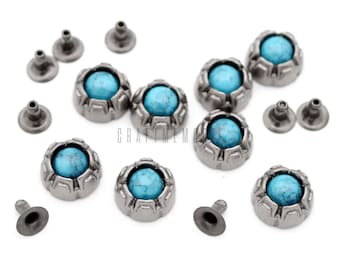 Op de afbeelding: Een set van tien turquoise en zilveren metalen studs. De studs hebben een decoratief, geometrisch ontwerp rond de turquoise stenen. De studs zijn perfect om een ​​toets van stijl toe te voegen aan lederwaren, kleding of andere ambachten.