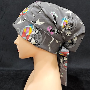 May include: Gray surgical scrub hat with a tie, featuring a colorful print of characters from the Nightmare Before Christmas.