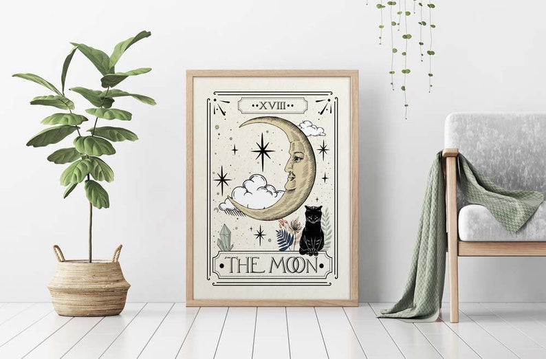 K&ouml;nnte beinhalten: Ein gerahmter Druck einer Tarotkarte, die die Mondkarte darstellt. Die Karte zeigt einen Halbmond mit einem Gesicht, eine schwarze Katze und Sterne. Die Karte ist mit "Der Mond" betitelt und mit "XVIII" nummeriert.