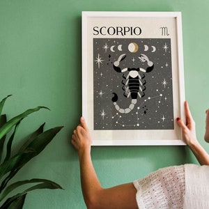 May include: A white framed print with a black background featuring a stylized scorpion illustration with a constellation of stars. The print has the text "SCORPIO" and the astrological symbol for Scorpio.