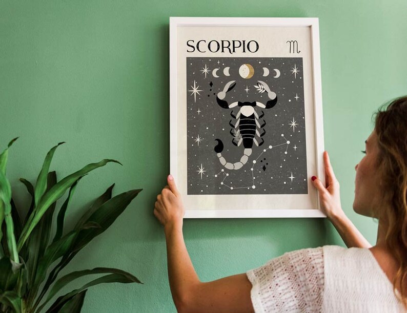 May include: A white framed print with a black background featuring a stylized scorpion illustration with a constellation of stars. The print has the text "SCORPIO" and the astrological symbol for Scorpio.