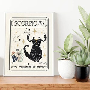 May include: A white framed print with a black cat illustration representing the Scorpio zodiac sign. The print features a constellation, stars, and the text "Scorpio ♏" and "LOYAL - PASSIONATE - COMMITMENT".